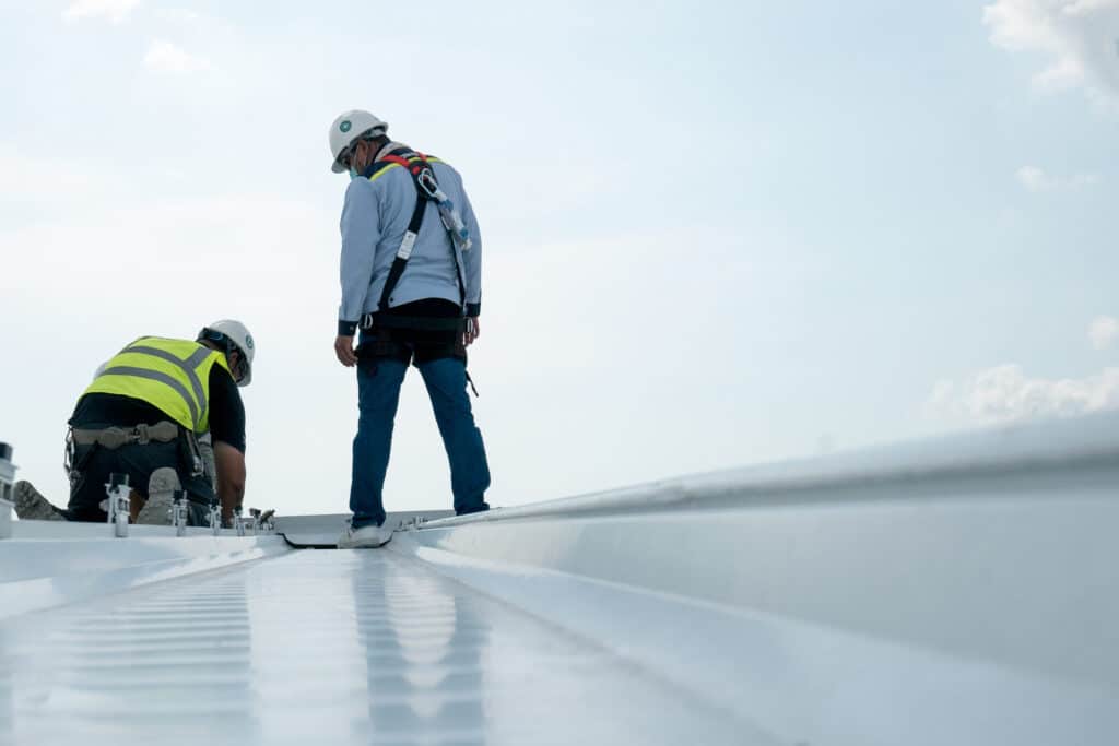 Two commercial roofers installing a roof for a business